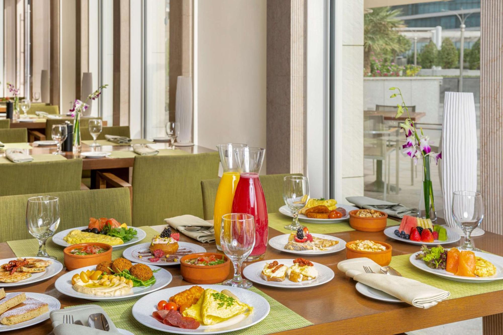 Hilton Riyadh Hotel & Residences Exterior foto The photo showcases a beautifully arranged dining table filled with a variety of dishes. There are multiple plates featuring an assortment of foods, including salads, appetizers, and main courses, presented in a vibrant and appetizing manner. Additio
